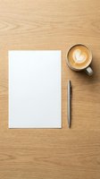 Blank white paper sheet with pen and coffee cup on wooden desk surface for business correspondence and creative writing projects.