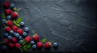 Fresh mixed berries strawberries and blueberries arranged on dark slate background with copy space for healthy eating and organic food concepts.
