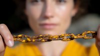 Rusty metal chain with flaking orange paint held in focus against blurred background, demonstrating decay and deterioration concept for industrial themes.