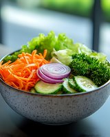 Fresh vegetable salad bowl with lettuce, carrots, cucumber, red onion and broccoli on kitchen counter for healthy eating and nutrition concepts.