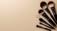 Professional makeup brushes set arranged in fan shape on beige background. Cosmetic tools for applying powder, blush, and eye shadow. Clean minimal composition.