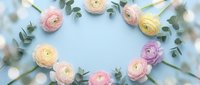 Pastel ranunculus flowers and eucalyptus leaves arranged in circular frame on soft blue background with copy space for spring wedding invitations and greeting cards.