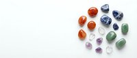 Collection of polished gemstones and crystals in various colors including carnelian, amethyst, aventurine and clear quartz on white background.