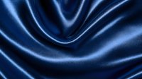 Luxurious navy blue silk fabric with elegant folds and waves creating smooth flowing curves. Soft textile background with glossy satin finish and gentle highlights.