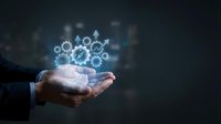 Businessman hand holding glowing gear mechanism hologram representing teamwork, innovation and business process optimization on dark background.