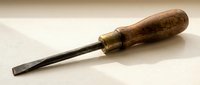Vintage wood chisel with brass ferrule and worn wooden handle on neutral background for woodworking and carpentry projects.
