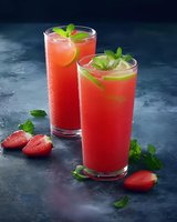 Fresh strawberry lemonade cocktails garnished with mint leaves and lime slices on dark background. Refreshing summer drinks with fresh berries and citrus.