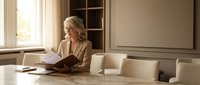 Professional blonde businesswoman reading documents in modern conference room with natural lighting for corporate presentations and meetings.