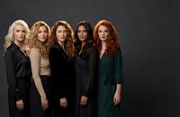 Five diverse professional women standing together in elegant business attire against dark background for corporate teamwork and leadership concepts.