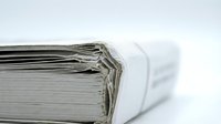 Stack of white paper documents bundled with rubber band on clean surface for office organization and filing systems.