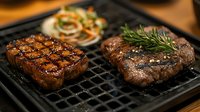 Grilled beef steaks with herbs on cast iron grill pan, perfectly cooked meat with grill marks and fresh rosemary garnish for culinary and restaurant menu use.