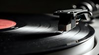Vintage turntable with vinyl record playing, retro music equipment with stylus and tonearm in dramatic lighting for audio and entertainment themes.
