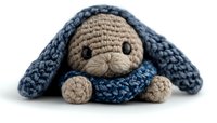 Handmade crochet bunny toy with long floppy ears in blue and beige colors lying on white background, amigurumi plush animal isolated for craft and hobby designs.