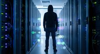 Silhouette of IT professional standing in modern server room corridor with glowing blue lights and data center equipment for technology concepts.