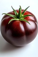 Fresh ripe dark purple heirloom tomato with green stem and water droplets on smooth skin, macro photography on white background for food marketing.