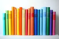 Colorful hardcover books arranged in rainbow order standing in row on white shelf, creating vibrant spectrum display for education and reading concepts.