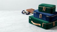 Colorful vintage suitcases stacked with leather accessories on white wooden surface for travel and vacation concepts.