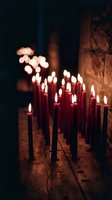 Red candles burning with warm flames creating atmospheric lighting on wooden surface in dark spiritual setting for meditation and prayer rituals.