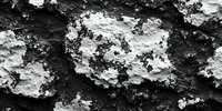 Rough textured lunar-like surface with contrasting black and white rocky formations creating dramatic shadows and depth for science or geology backgrounds.