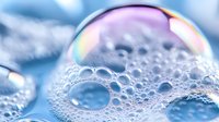 Soap bubble with rainbow iridescent surface and foam texture against soft blue background. Macro photography showing delicate spherical form and colorful reflections.