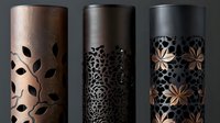 Decorative metal cylinders with laser cut floral patterns in copper, bronze and black finishes. Elegant oriental style lanterns showcase intricate botanical designs.