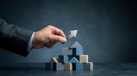 Businessman hand placing wooden block on stack, symbolizing growth, success, and business development strategy.