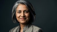 Confident mature Hispanic businesswoman with gray hair smiling warmly against dark background, representing leadership and professional success in corporate environment.