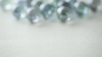 Blurred glass marbles on soft textured surface creating dreamy bokeh effect with copy space for text overlay and graphic design projects.