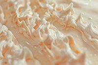 Soft waves of whipped cream in peach and white tones create delicate texture and pattern, macro photography shows intricate details of sweet dessert topping.
