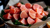Fresh raw salmon cubes with herbs and lemon on brown paper, ready for cooking. Close-up view of diced pink fish fillet pieces garnished with dill.
