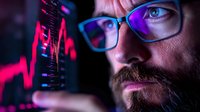 Bearded man in glasses illuminated by vibrant neon lights examines financial data charts and market trends on digital display in dark environment. Professional trader analyzing statistics.