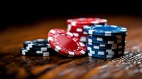 Stacked poker chips in red, blue, and black on wooden surface with dramatic lighting and shallow depth of field, creating atmospheric casino gaming ambiance.