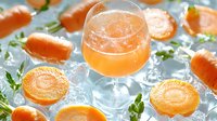 Fresh citrus cocktail in elegant glass surrounded by orange slices, crushed ice and mint leaves on bright background, refreshing summer drink concept.