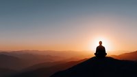 Person meditating on mountain peak at sunrise with layered hills and golden sky creating peaceful mindfulness scene for wellness and spiritual content.