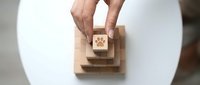 Hand placing wooden block with paw print icon on stack, symbolizing pet care services, animal welfare, veterinary concepts for business branding.
