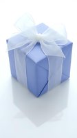 Blue gift box with white organza ribbon bow isolated on white background for special occasions and celebrations.