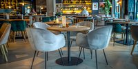 Modern restaurant interior with comfortable gray upholstered chairs and wooden tables, featuring ambient lighting and contemporary decor in warm tones. Stylish dining space.