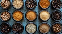 Variety of aromatic spices and peppercorns in black bowls arranged in rows on dark background, overhead view showing texture and colors of cooking ingredients.