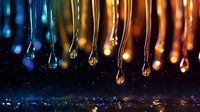 Glowing water drops falling against dark background with bokeh lights and reflections create magical atmosphere for abstract backgrounds and wallpapers.