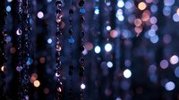 Elegant crystal beads hanging in chains create magical bokeh lights effect with purple and blue tones for luxury decoration and festive atmosphere.