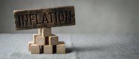 Wooden blocks stacked with inflation sign on top, representing economic pressure, rising costs, and financial burden in business and economy.