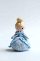 Handmade knitted princess doll in blue dress with blonde hair bun isolated on white background for crafts and children toys.