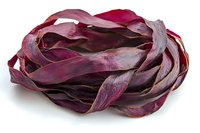 Fresh purple cabbage peels arranged in artistic spiral pattern on white background, showing natural organic texture and vibrant burgundy color. Isolated food photography.