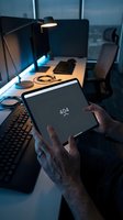 Person holding tablet displaying 404 error in modern office workspace at night with computer monitor, keyboard, desk lamp and city skyline view through windows.