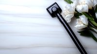 Minimalist flat lay with black modern door key and white peonies on light wooden background, space for text. Real estate or new home concept.
