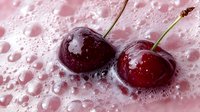 Fresh ripe cherries with water droplets on pink background, showcasing juicy texture and natural freshness for food photography and culinary design.