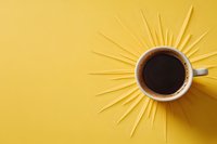 Hot coffee cup on yellow background with sun rays made from wooden sticks, creative minimal morning concept composition for cafe menu or social media post.