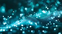 Magical turquoise bokeh lights and glowing particles flowing in dark space create dreamy atmospheric background for festive designs and holiday projects.
