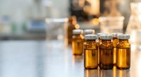 Medical amber glass vials with rubber stoppers arranged on laboratory table for pharmaceutical research and drug development applications.
