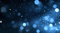 Dreamy blue bokeh lights on dark background with glowing particles and blurred circles create magical atmospheric effect for festive designs.